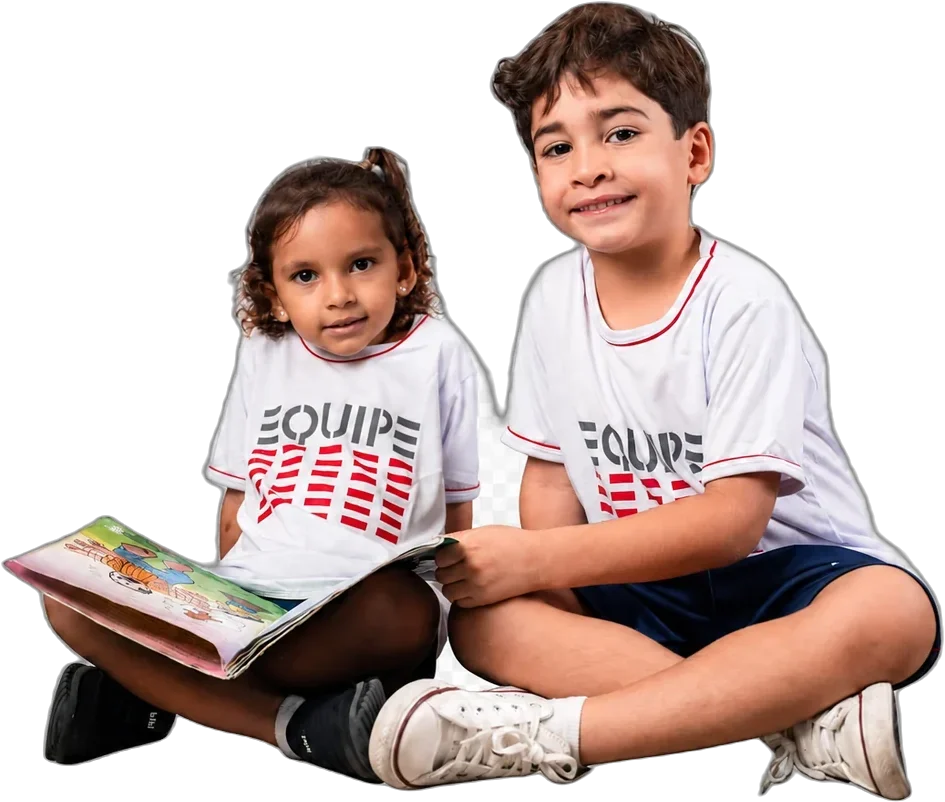Duas crianças da Educação Infantil sentadas lendo um livro juntas